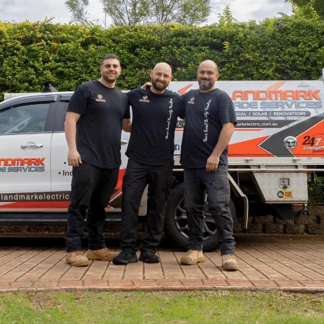 The Landmark Electrical team beside a branded work ute in a Sydney driveway